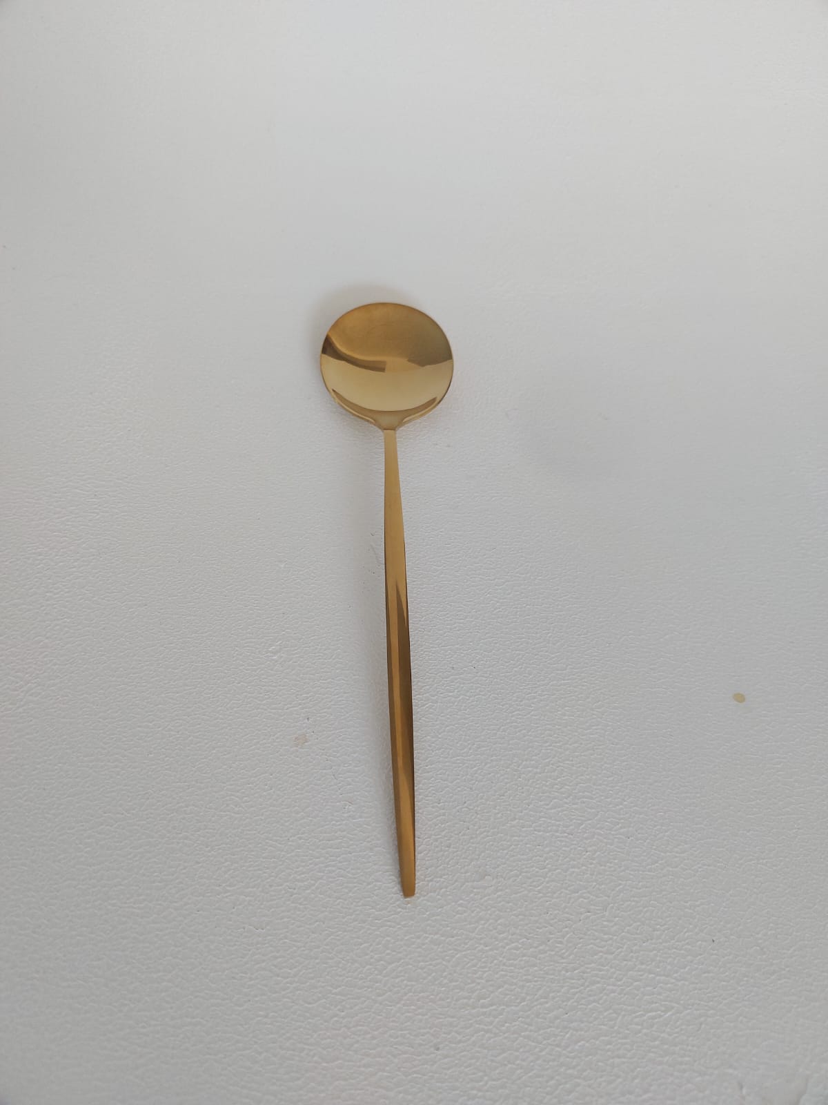 Rounded gold dessert spoon